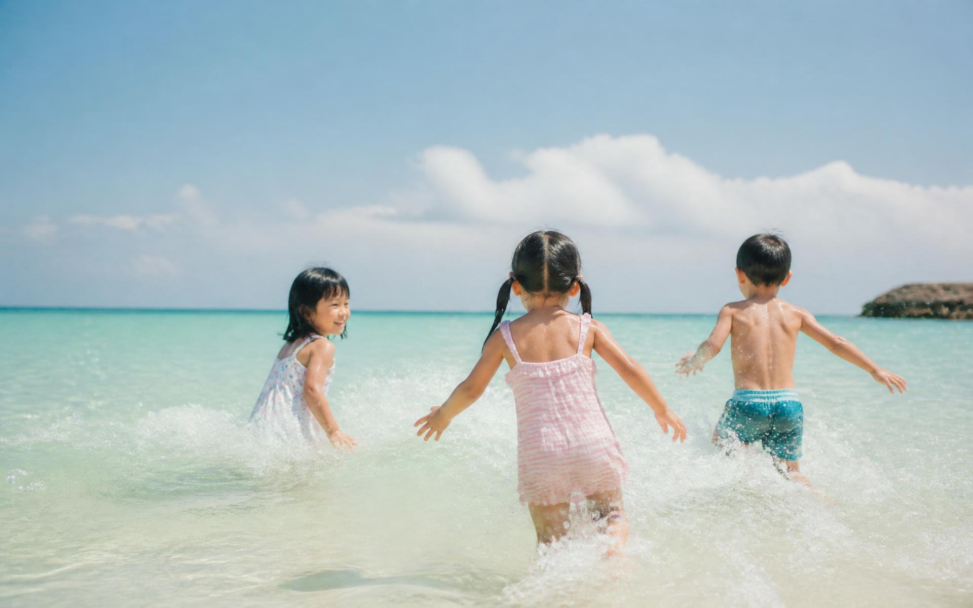 海辺で笑顔を交わす子どもたち。
